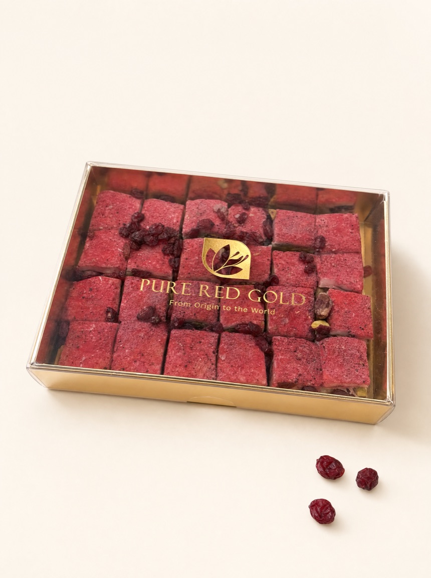 Gold box with a clear lid holding rows of crimson red berry sweets scattered with dried berries, gold Pure Red Gold wordmark printed on the lid